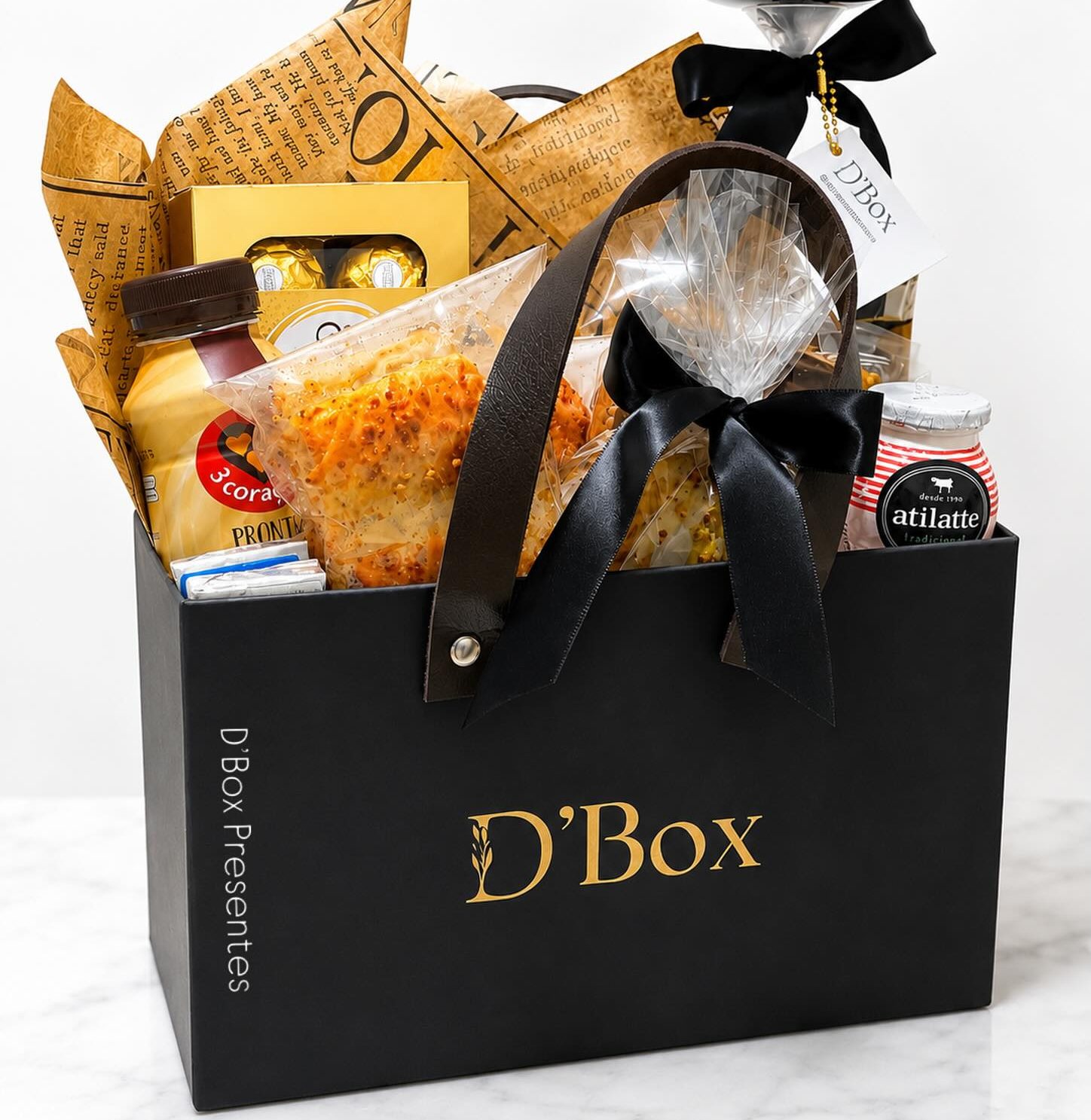 Cesta de café da manhã da D'Box: sacola preta com o monograma dourado, laço de cetim preto e balão personalizado